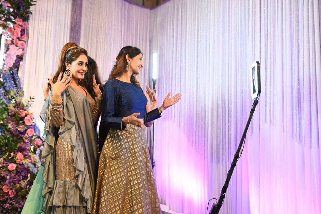 Guests in Indian outfits posing on the 360 video booth platform with LED lighting