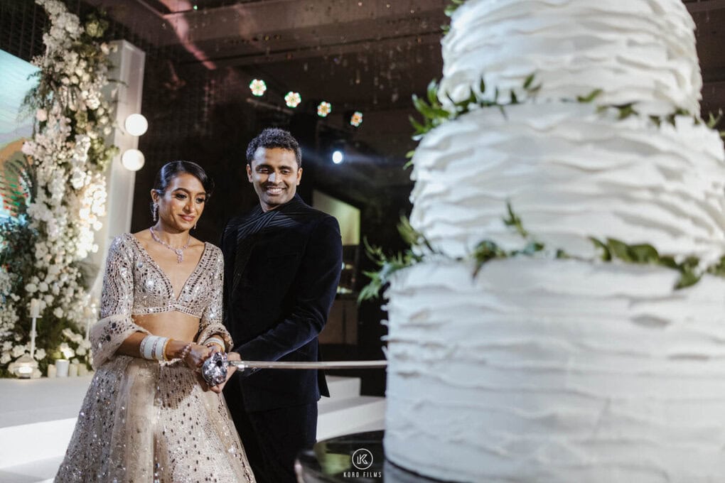 Tarun and Sasha cut their wedding cake with a sword at their reception at Four Seasons Hotel Bangkok