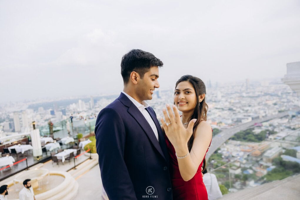 A newly engaged couple shows the ring on the rooftop of Lebua at State Tower with the Bangkok skyline behind