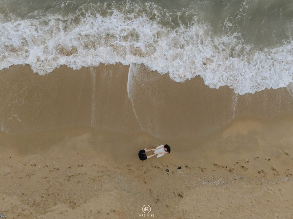 Drone view of Benji and Lhazom on the sand as waves roll in at Rayong Beach