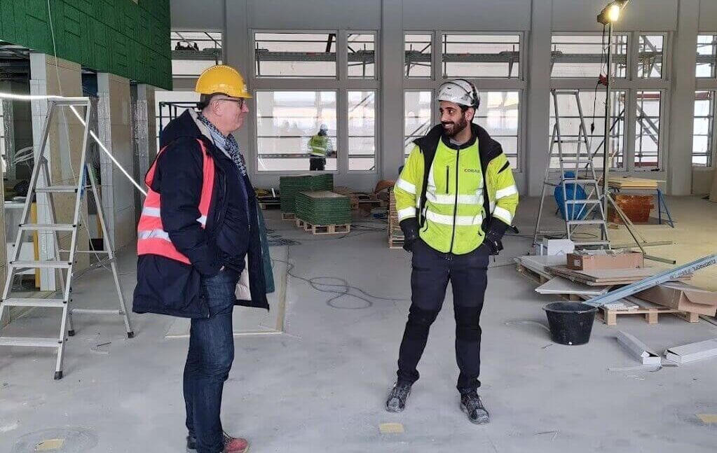 Konstruktionsarbete med två män i skyddsglasögon och hjälmar på en byggarbetsplats för el och vatteninstallation i ett nytt byggprojekt.