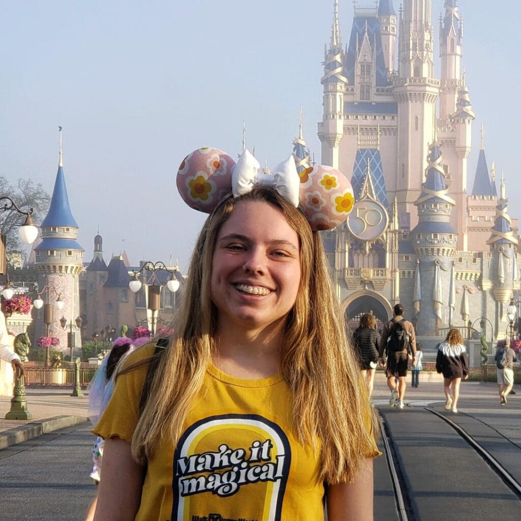 Disney castle with young woman enjoying the theme park experience.