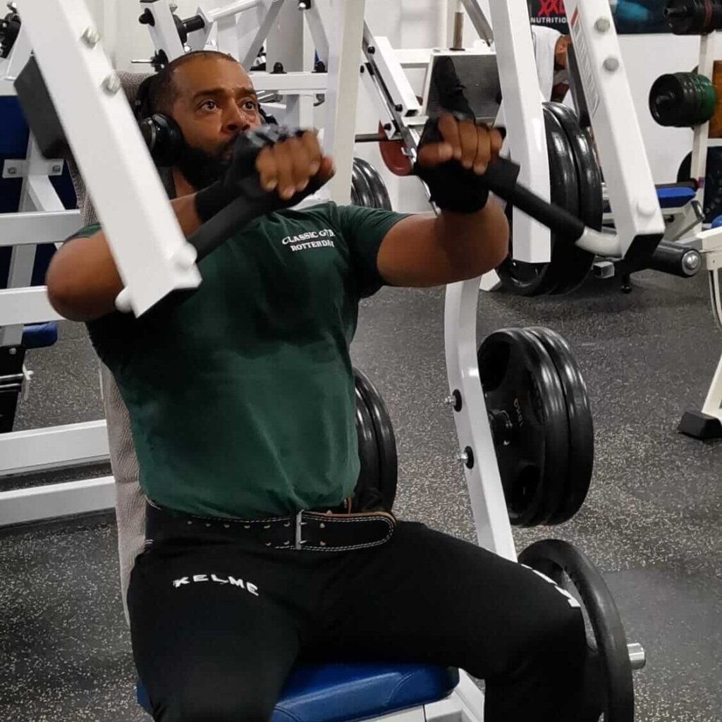 Man voert een incline chest press uit op een Hammer Strength free-loaded machine, gefocust op kracht en stabiliteit.