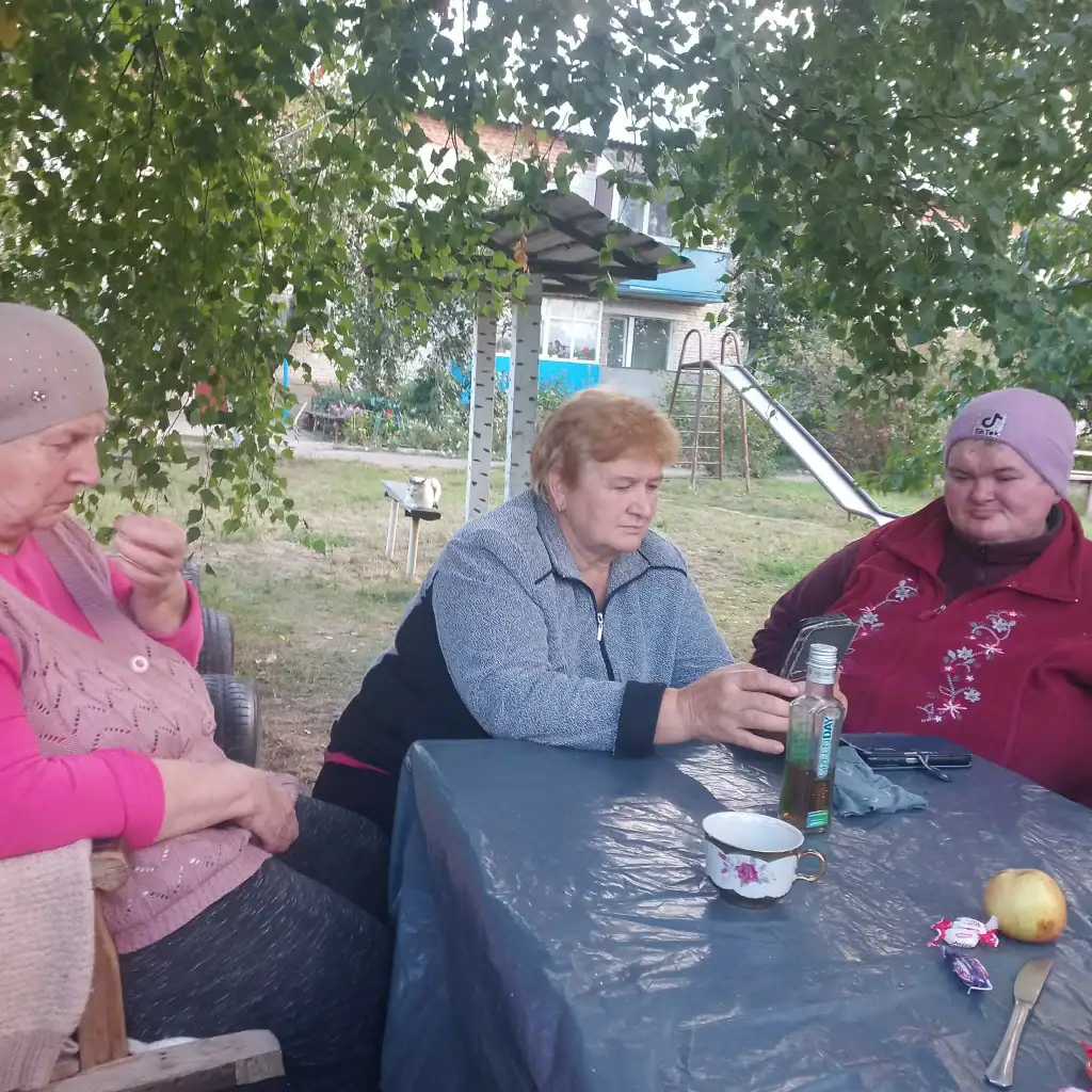 Жінки за столом під деревом у прифронтовій Кириківці на Сумщині