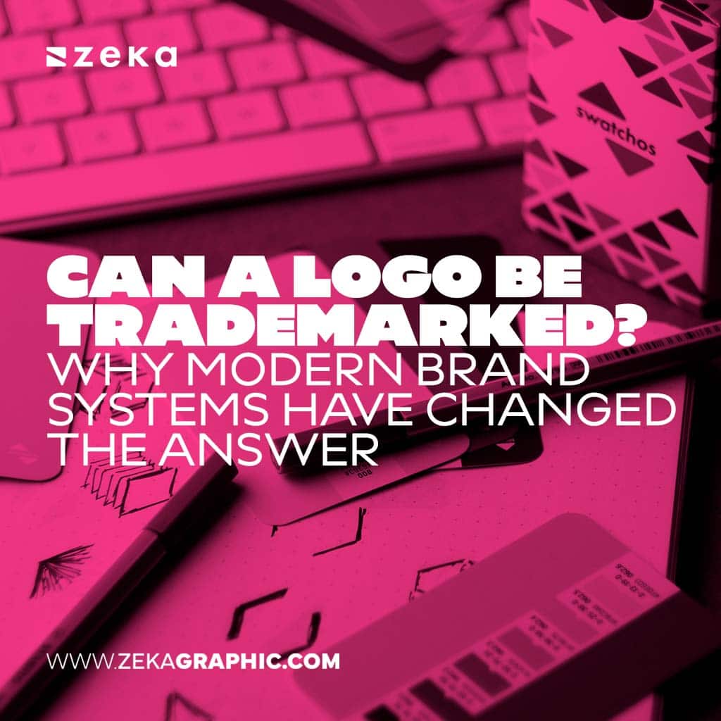 Hot pink duotone vertical image of a desk with a computer keyboard, a stylus, and a sketchbook with logo drawings, featuring bold white text reading Can a Logo Be Trademarked? Why Modern Brand Systems Have Changed the Answer.