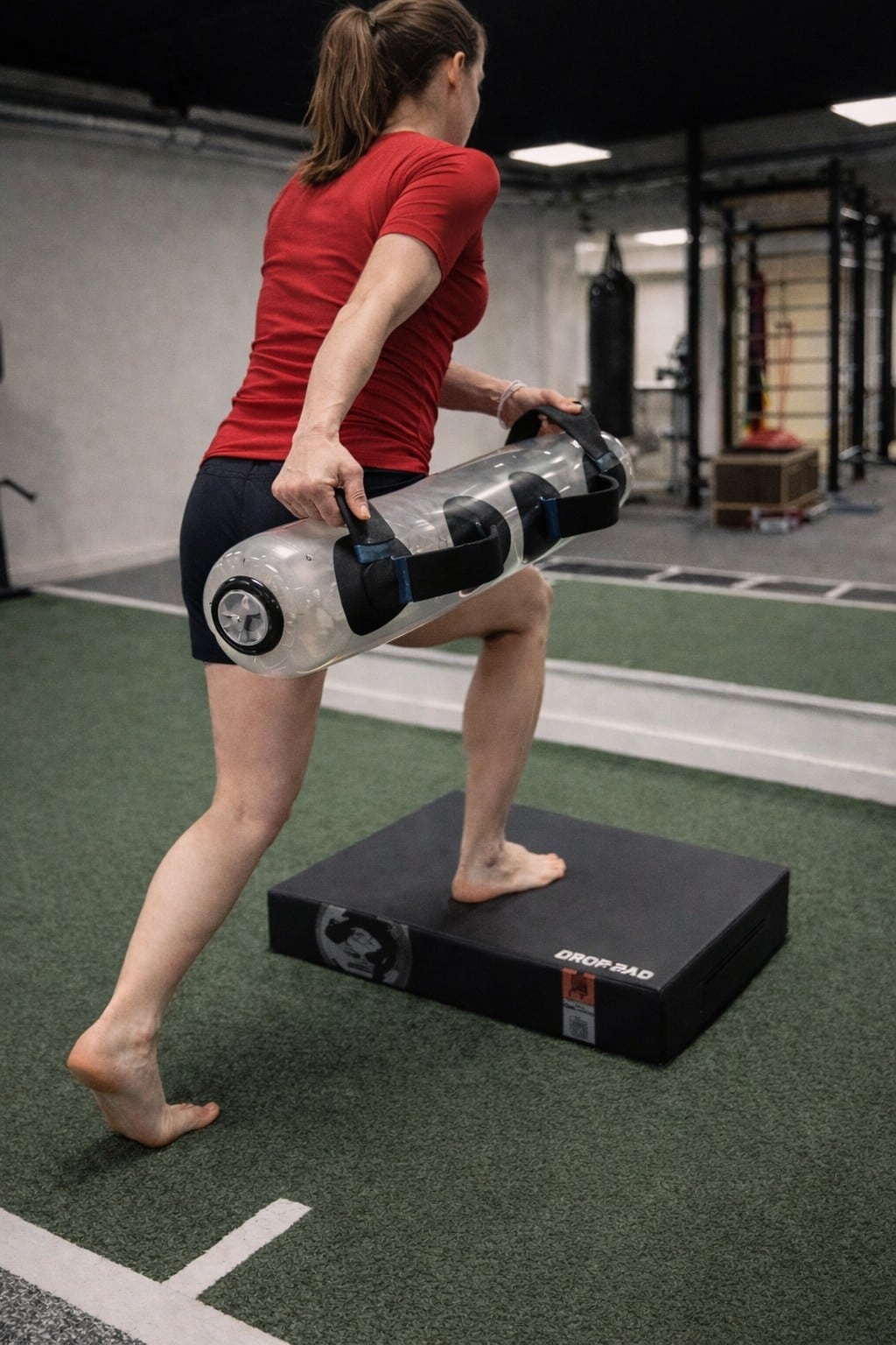 Sportkinesitherapie oefening met step-up en waterbag voor kracht en stabiliteit in Haacht
