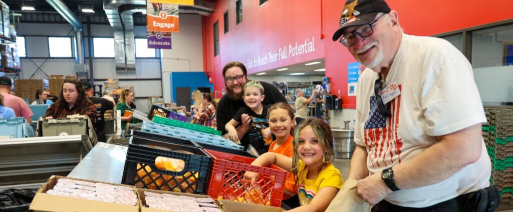 Diverse group of volunteers packing sack lunches at Kids' Food Basket