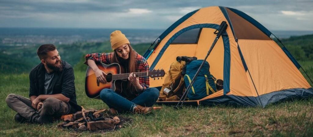 jeune femme jouant sa meilleure guitare de voyage en camping