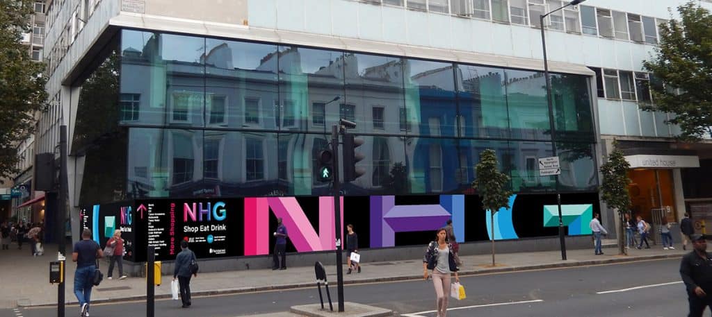 Black vinyl hoarding with Notting Hill Gate branding and directional information applied to the glass frontage of a shop