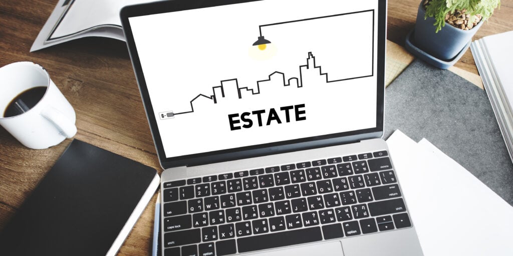 A computer on a table with a open website for real estate netx a cup o f coffee