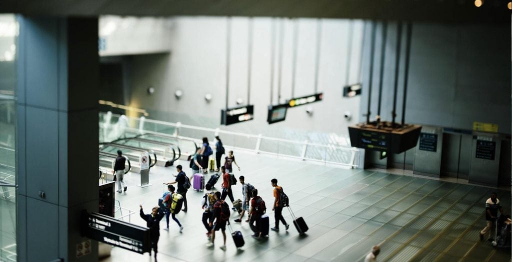 Travelers with luggage at an airport terminal, illustrating expats arriving in France needing health insurance