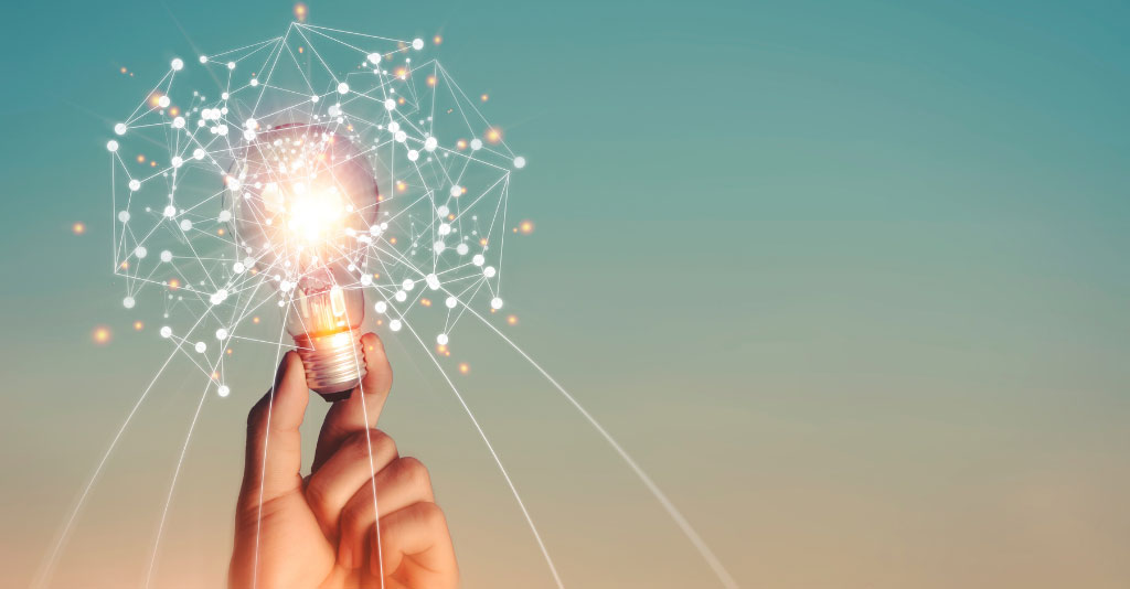 Image of a person holding a lightbulb surrounded by glimmers of light.