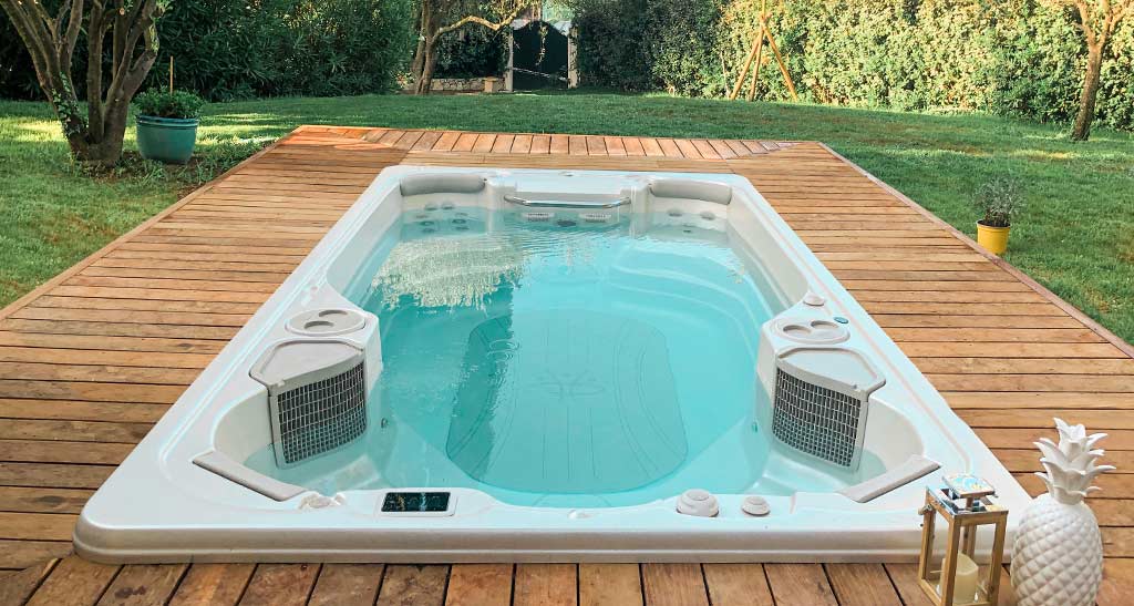 Spa de nage 14AX encastré dans une terrasse en bois dans un jardin.