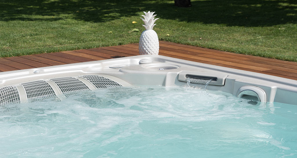 Spa de nage 19EX encastré dans un jardin vu de près avec un ananas blanc.