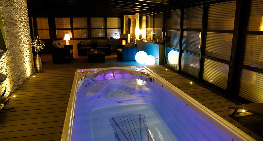 Spa de nage 19EX en intérieur éclairé en bleu.