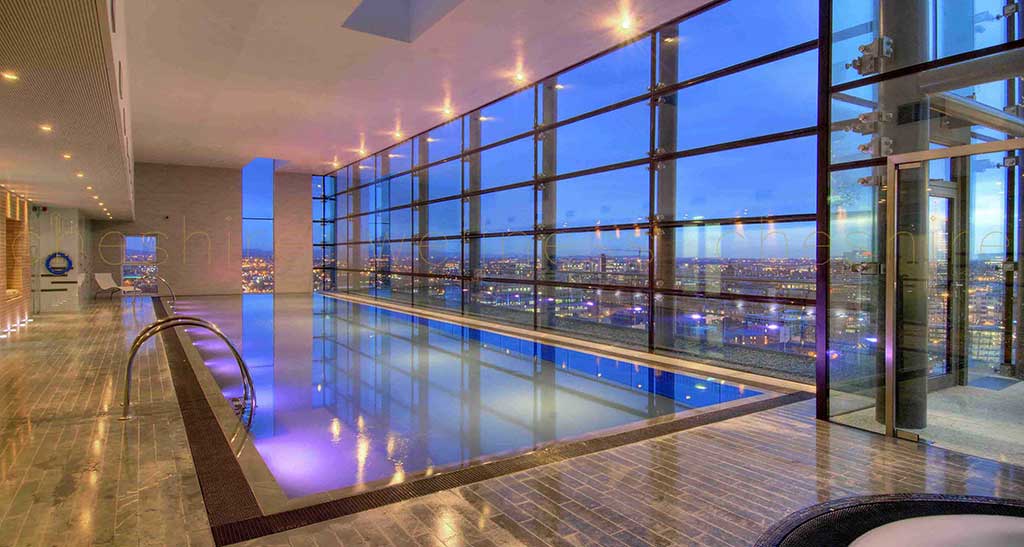 Piscine sur-mesure avec vue sur ville illuminée.