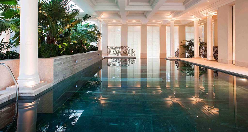 Piscine sur-mesure dans un espace bien-être avec des colonnes et des plantes.