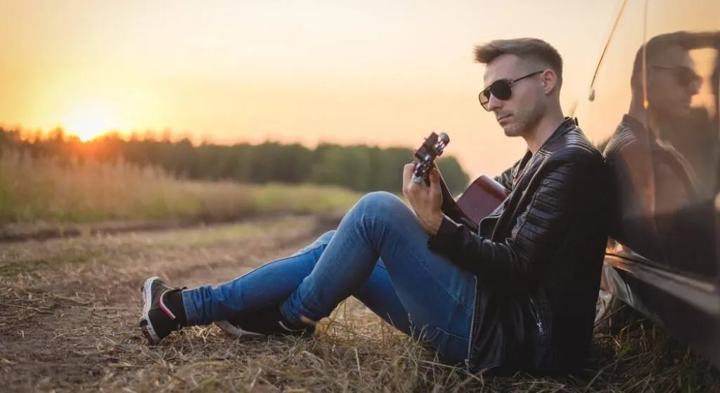 Homme jouant sa meilleure guitare de voyage au bord de la route