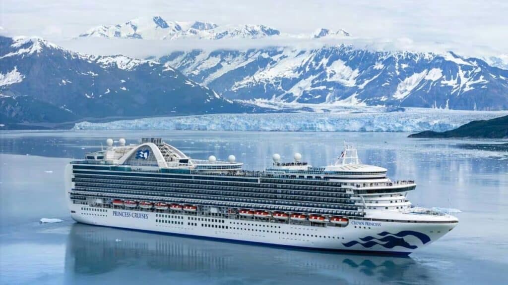 Elegant cruise ship sailing through icy fjord with snow-capped mountains.