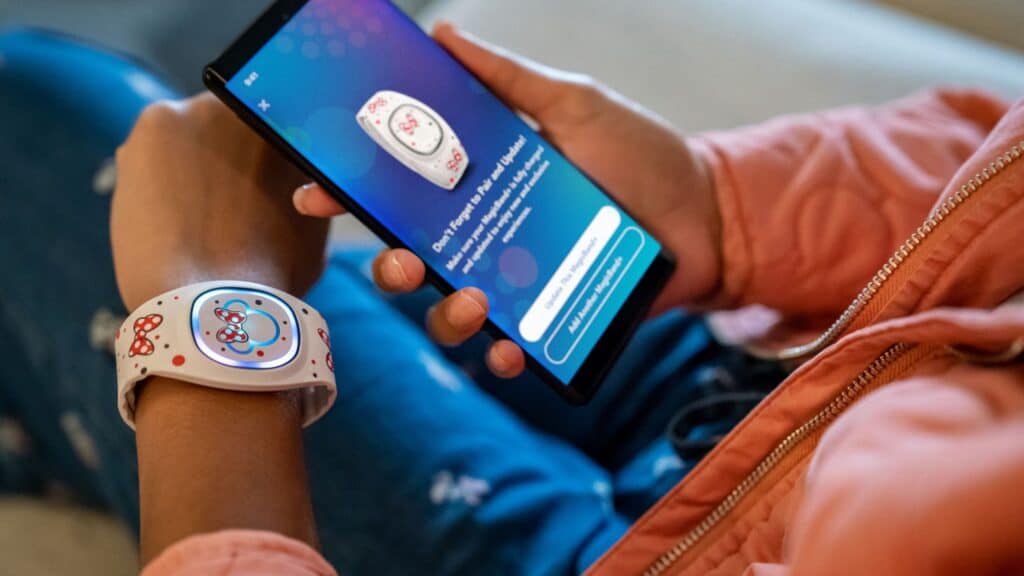 Person using a smartphone with Disney World Vacation Calculator app on their wrist and phone.