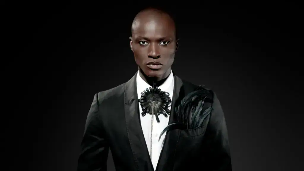 ein model in einem eleganten schwarzen anzug mit einzigartigem schmuck und einem dramatischen hintergrund.