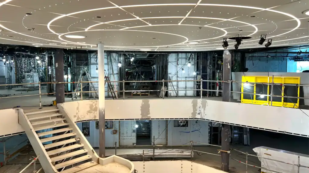 das_atrium_auf_der_mein_schiff_relax - Michis Kreuzfahrten blick auf den innenraum eines kreuzfahrtschiffes während der bauarbeiten, mit einem geschwungenen deckenbeleuchtungskonzept und einer offenen treppe.