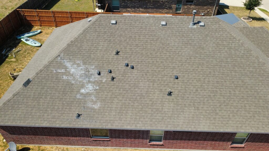 Aerial drone inspection photo of an asphalt shingle roof in Dallas–Fort Worth showing granule loss and impact marks across the shingle field