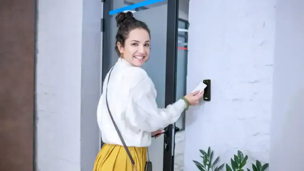 Woman using a key card to unlock a door with an IPROTECT access control reader