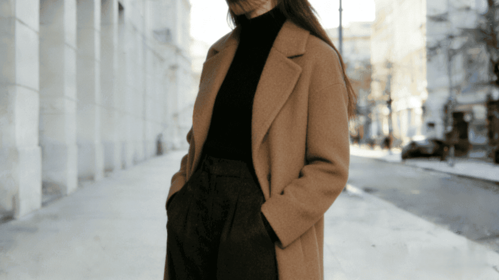 Minimalist winter streetwear: Camel wool overcoat, black turtleneck, and charcoal wide-leg trousers – elevated neutral-toned daily outfit