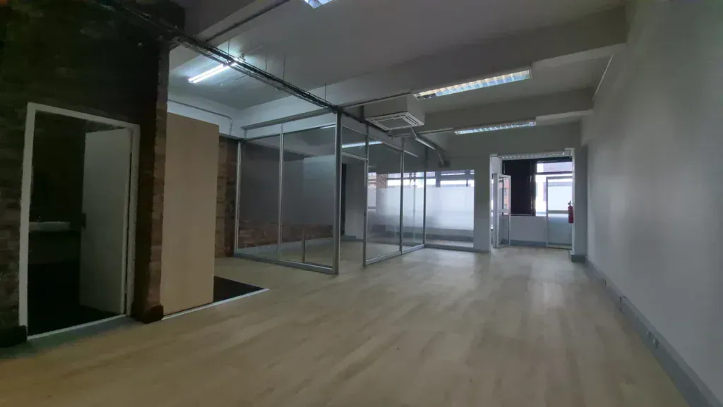 Empty, vacant commercial office space with glass partitions and hardwood floors. It illustrates high commercial real estate vacancy rates and available property rentals in the city.