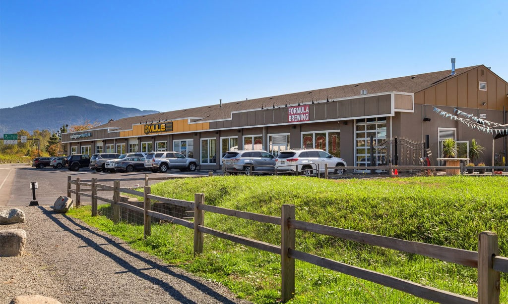 1875 Nw Poplar - Strip mall with parked cars and mountain backdrop on a clear day