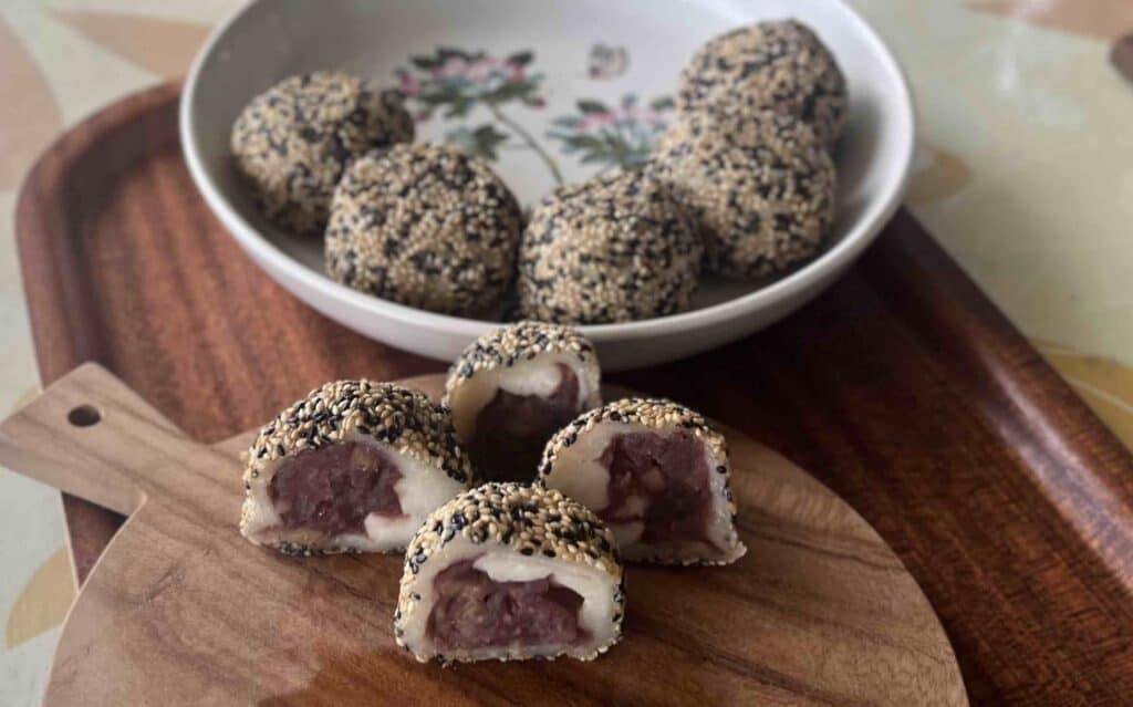 皿に入った出来上がりの胡麻団子とカットされてまな板に乗ったあんこの断面が見える胡麻団子