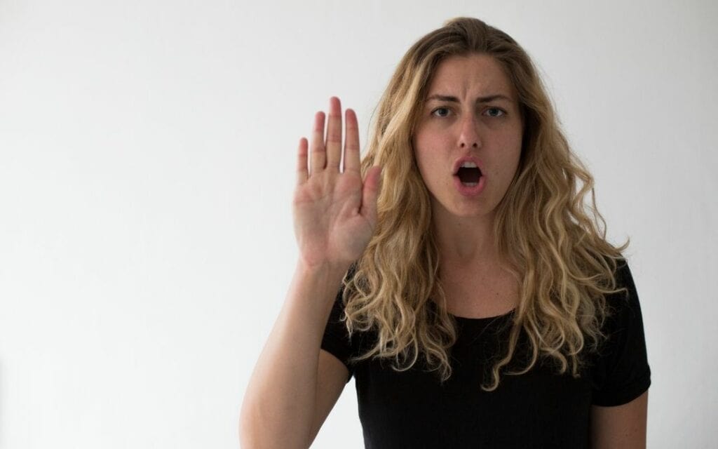 Eine Frau hält die Hand stoppend hoch und formt den Mund zu was "Stop" heissen könnte: Wut hilft Grenzen setzen
