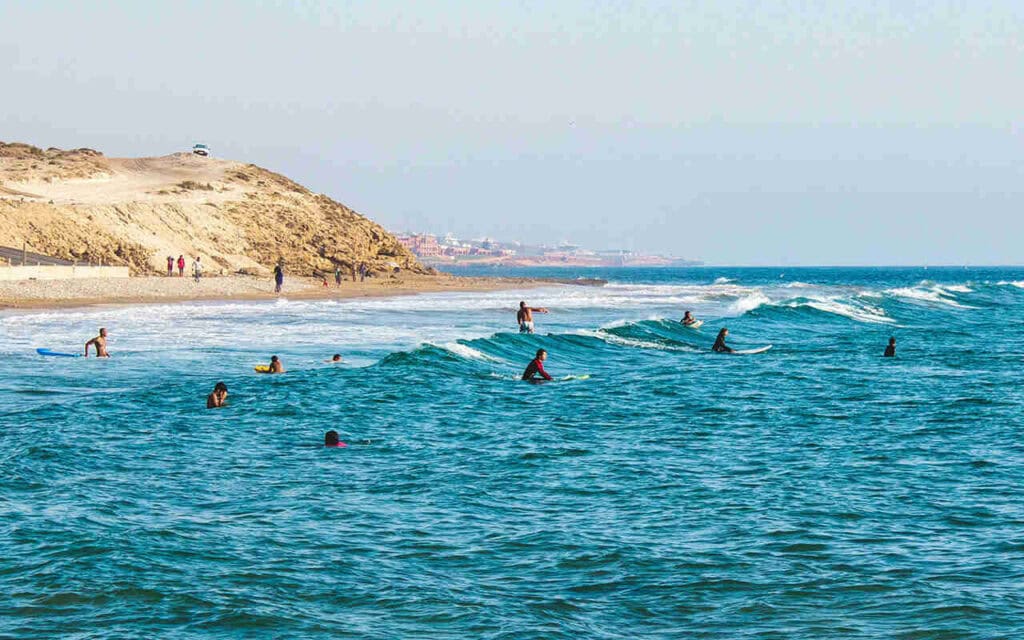 surfers sitting in the water on a beach in agadir morocco