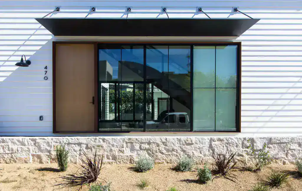 Modern minimalist house exterior with large glass window and wooden door.