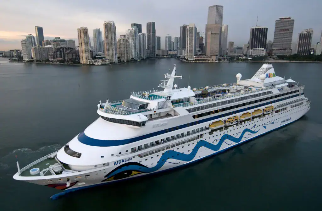 PM_Bild_AIDAaura_Miami-1024x672 - Michis Kreuzfahrten die aidaaura, ein kreuzfahrtschiff, fährt entlang einer stadtlandschaft mit hohen gebäuden im hintergrund.