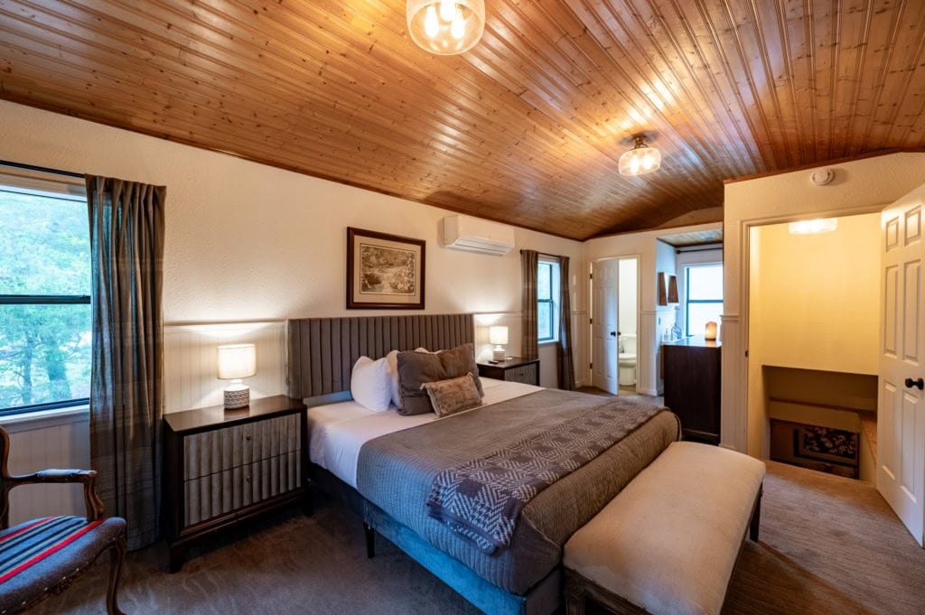 A cozy bedroom in a rustic Eureka Springs cabin with wooden ceiling and modern amenities.