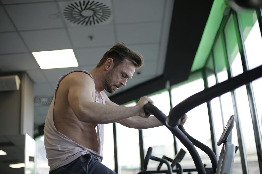 strong sportsman using exercise bike during cardio workout in gym