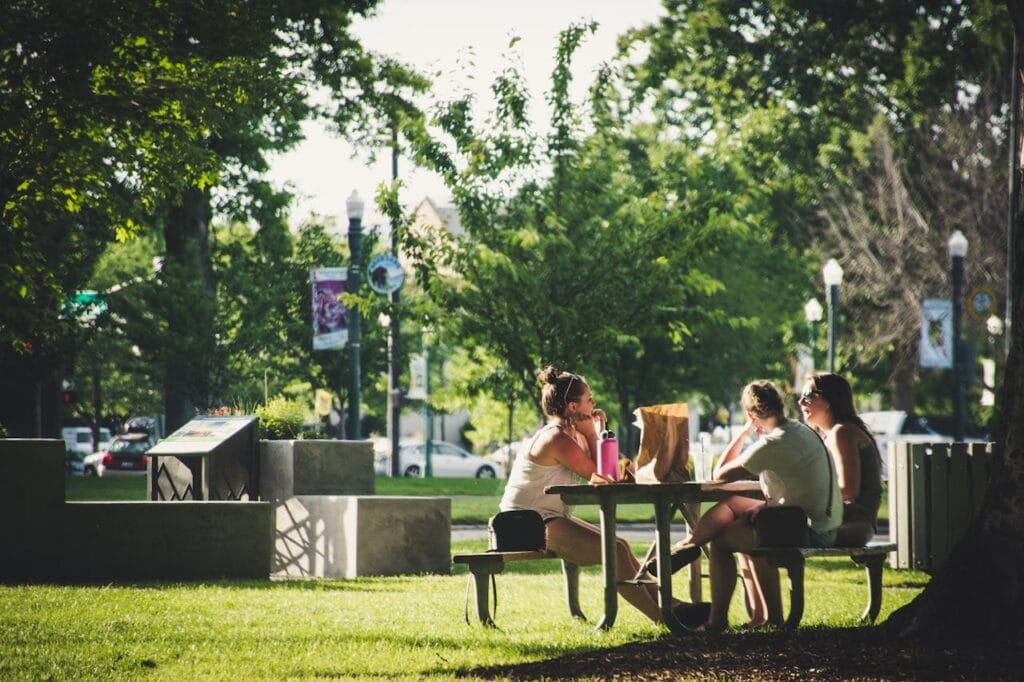 Three Women Sitting On Benches at a Public Park