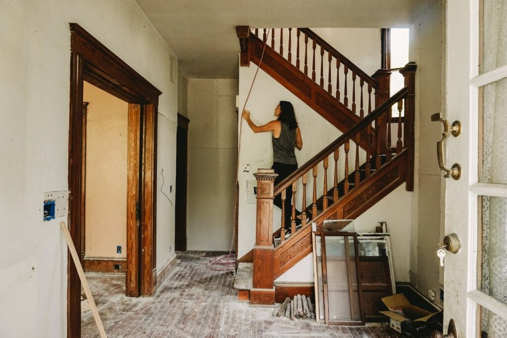 A Woman in Gray Tank Top Standing on Wooden Staircase in a Fixer Upper Home