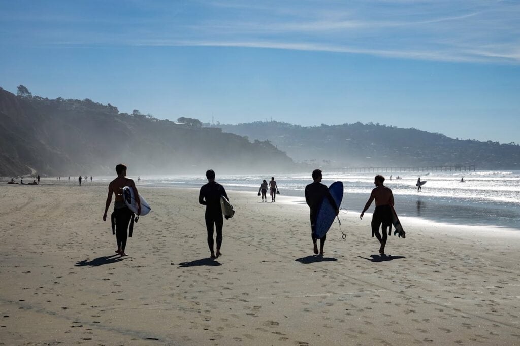 Silhouettes of People Walking with Their Surfboards in a San Diego Beach