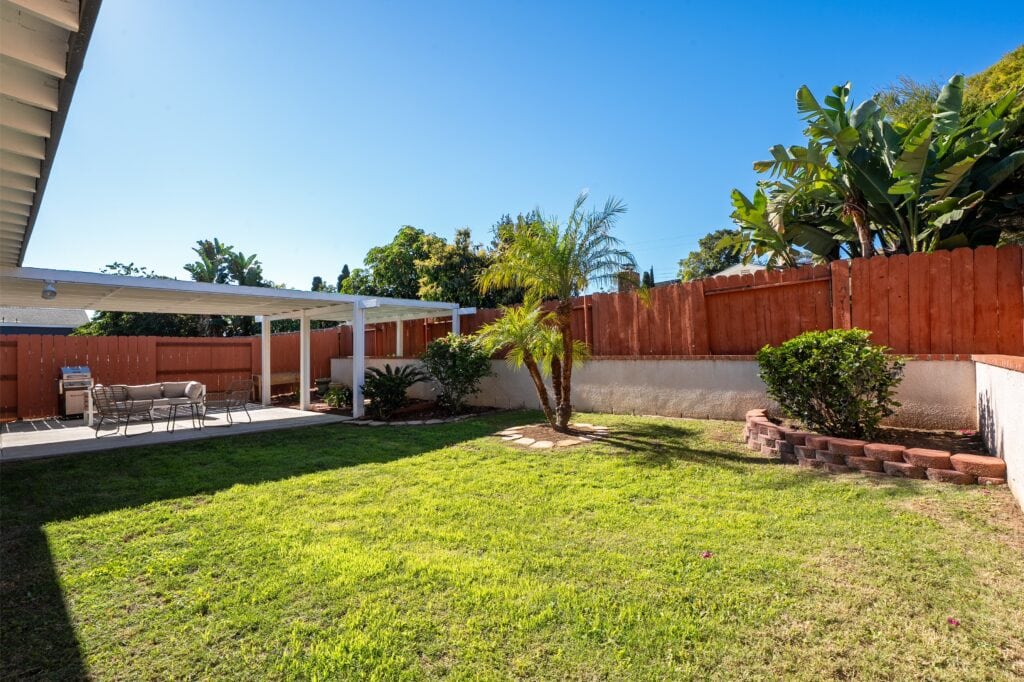 Wide view of the secluded retreat backyard at 2170 Montclair St in North Park, showing the expansive lawn, weather-protected pergola, and lush greenery.