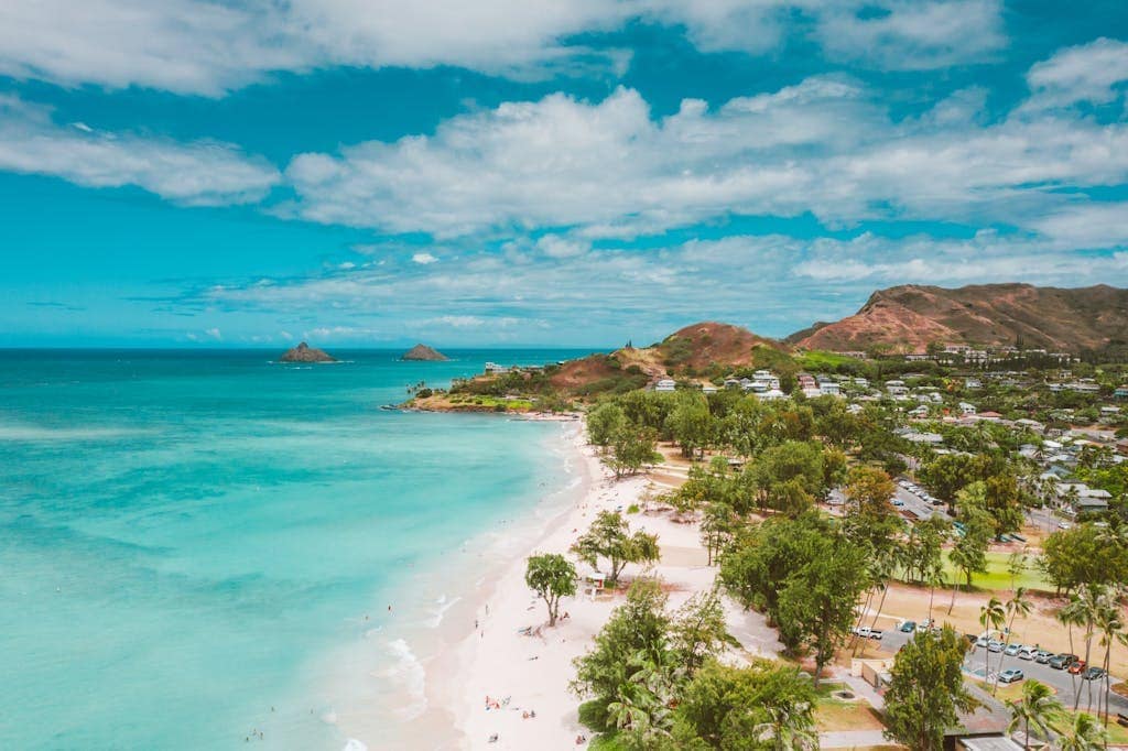 Explore a picturesque tropical beach in Hawaii with turquoise water and lush greenery.