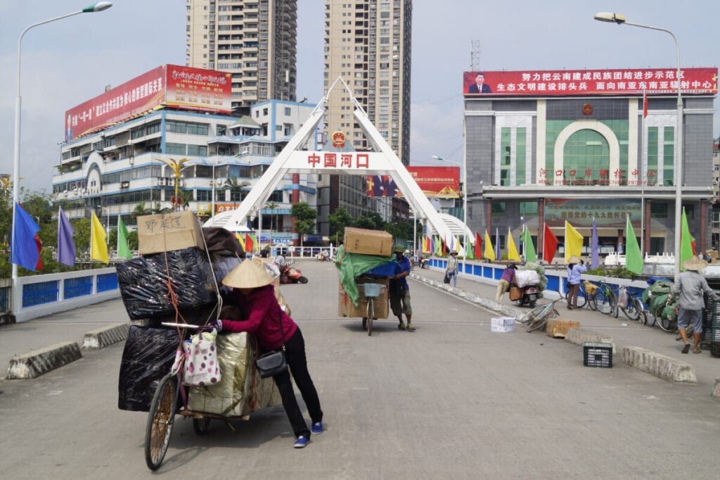 Cruzando el Puente entre Hekou y Lao Cai Personas arrastrando bicicletas con cajas en el Puente entre Hekou y Lao Cai