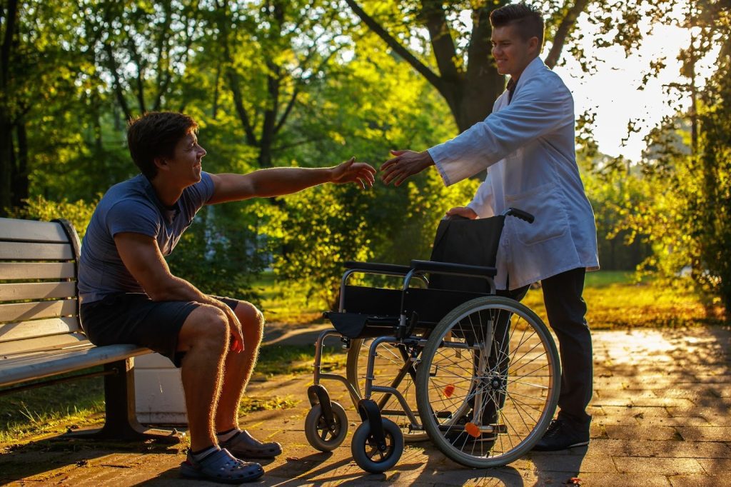 Caretaker trying to help a differently abled person get up