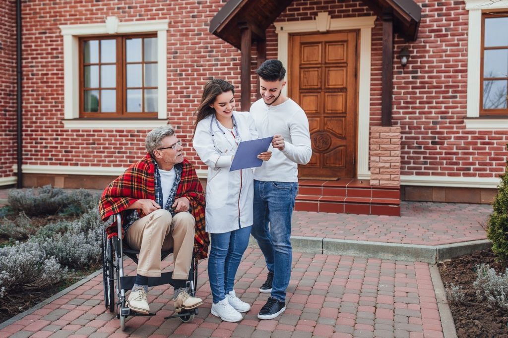 A doctor and a man standing beside a person in wheelchair