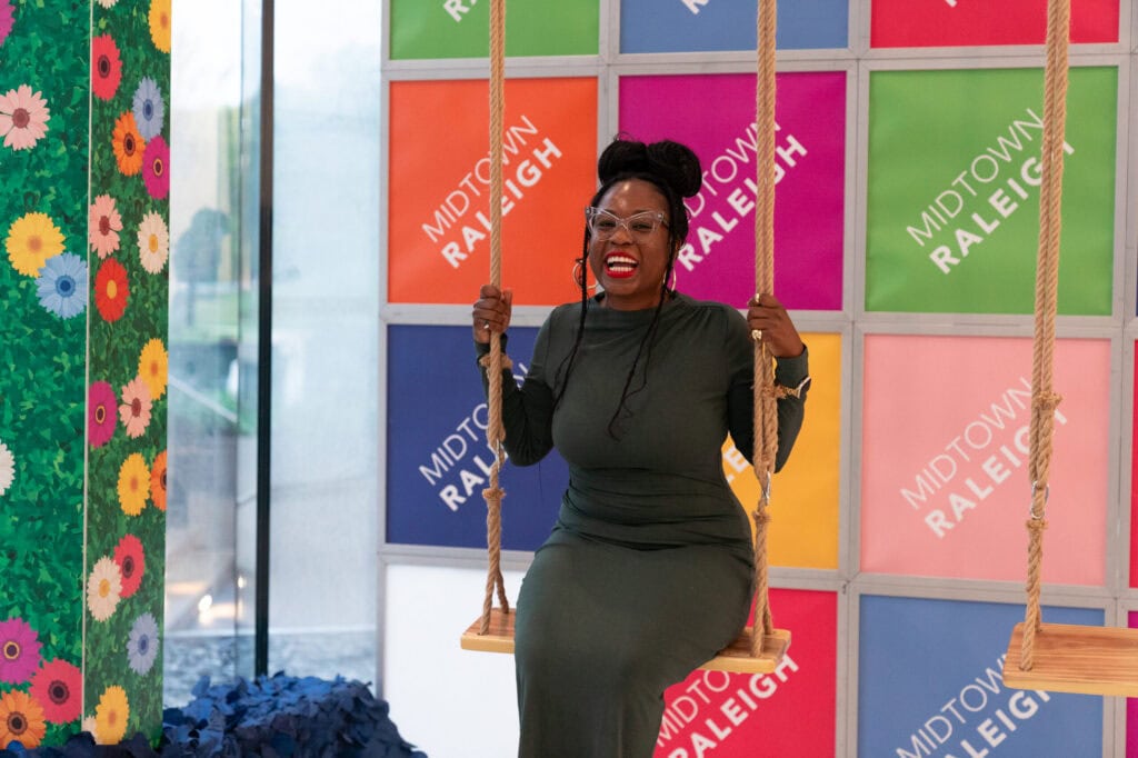 A smiling woman sits on a swing at MRA's State of Midtown celebration