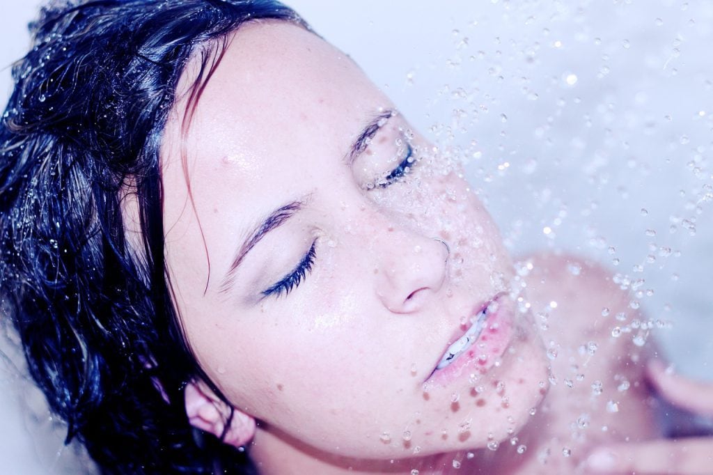 Image of lady dark hair of shower with water cascading down onto her face.
