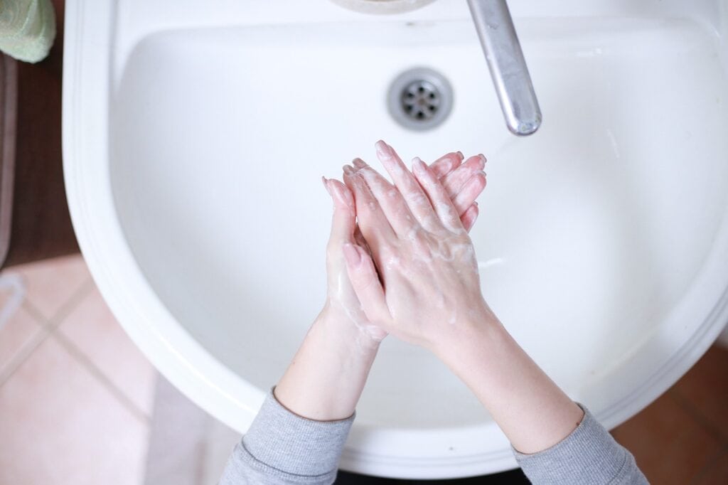 Hands being washed above sink using warm water generated by a hot water installation.