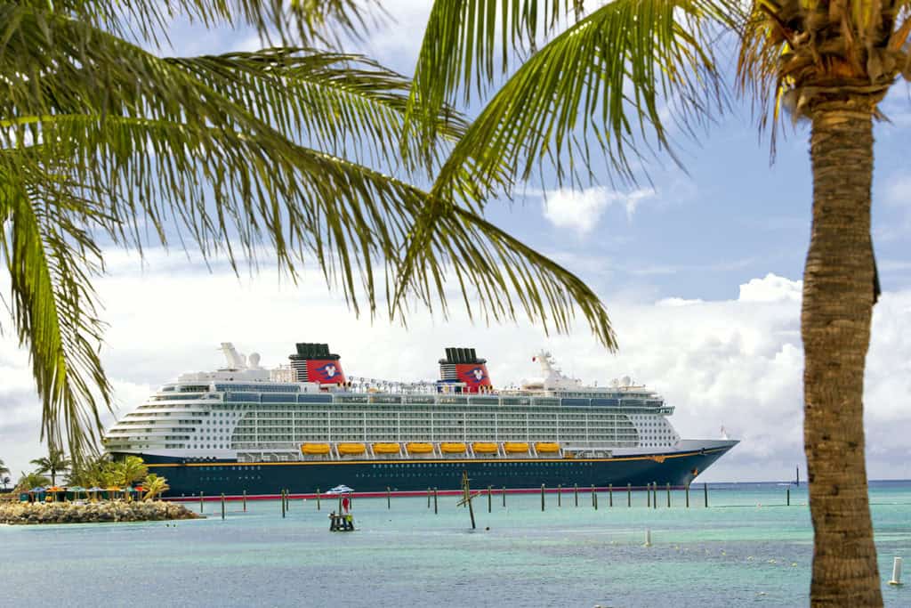 Luxurious cruise ship docked at tropical island with palm trees and clear blue waters, perfect for exotic vacations.